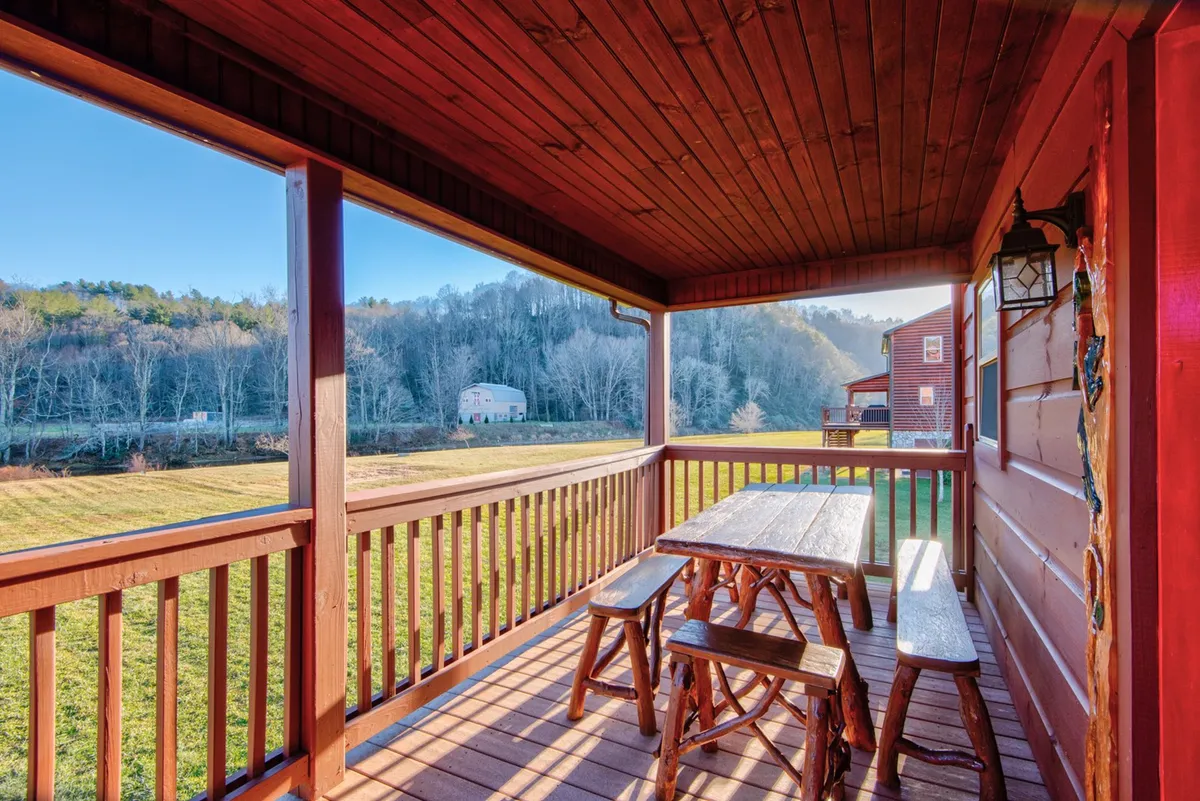 A peaceful wooden deck featuring a picnic table and surrounded by a scenic landscape. The space is ideal for outdoor dining or simply relaxing while taking in views of the countryside and river.