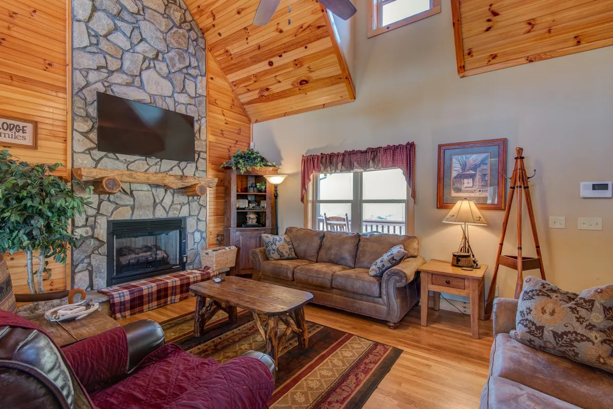 This interior scene spotlights a stone fireplace surrounded by comfortable seating, wooden beams, and large windows. The area radiates warmth and coziness, perfect for cuddling up after a day of mountain exploration. The fireplace, a focal point, hints at intimate evenings spent together, possibly with hot cocoa or a good movie.