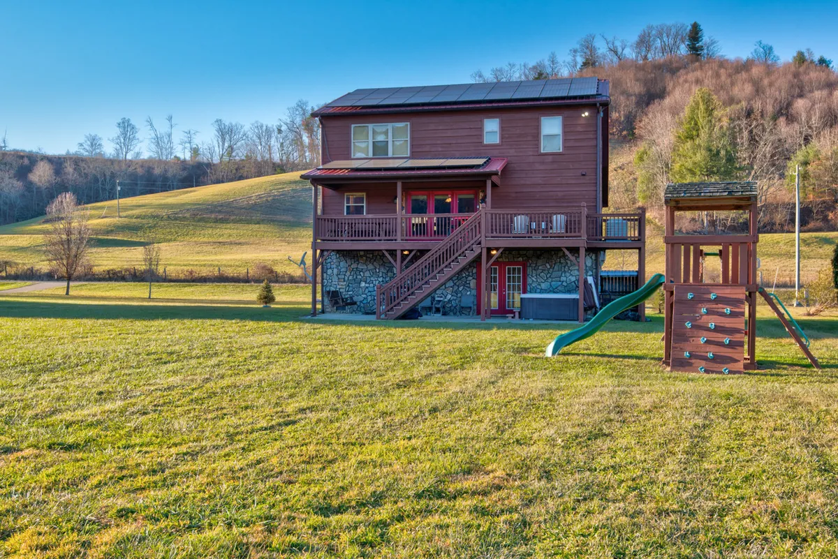 A cheerful exterior scene featuring a wooden house, green lawn, and playground equipment, where children can play and families can gather outdoors for barbecues or games.