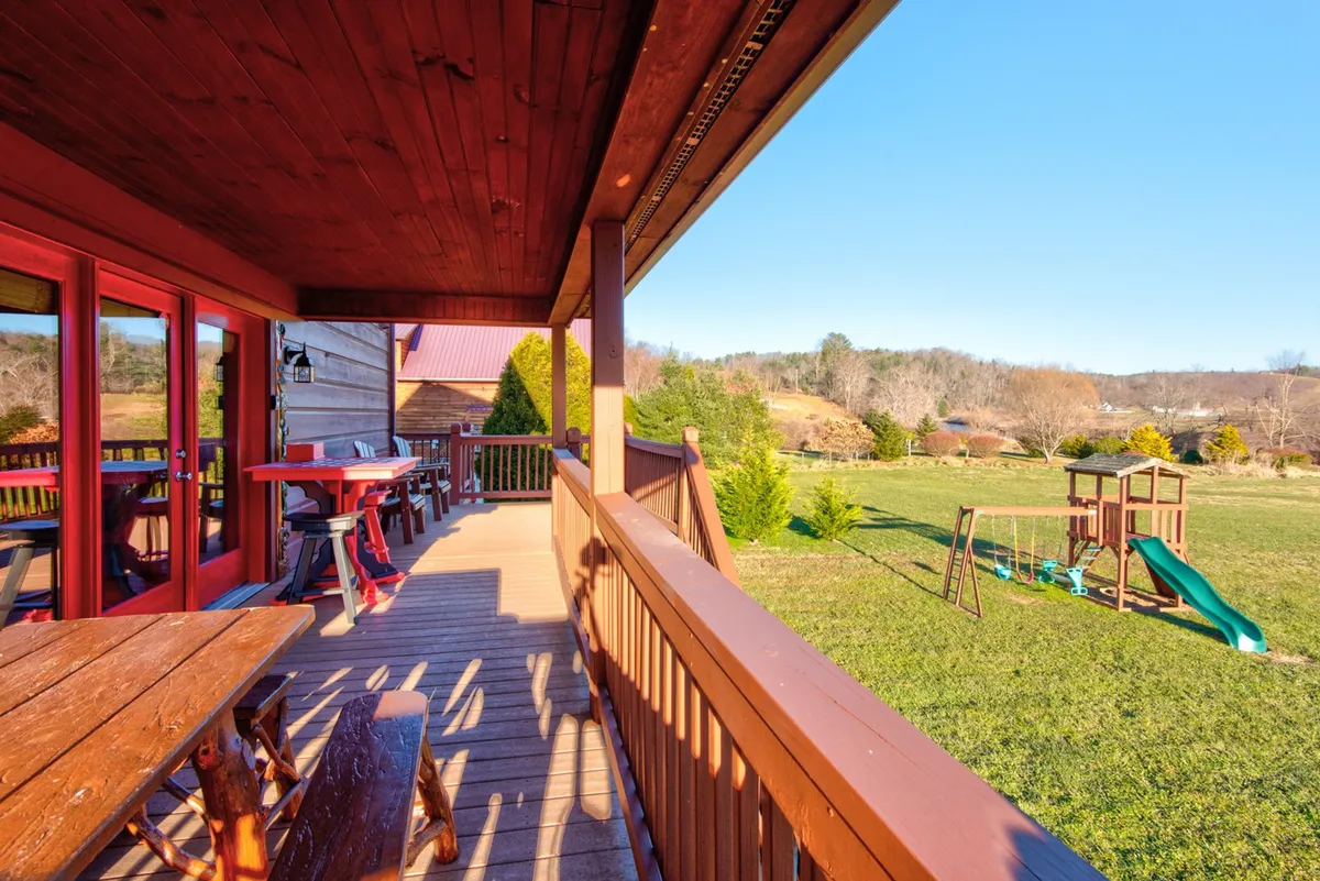 This exterior shot highlights a wooden deck overlooking a green lawn and playground equipment, with a beautiful mountain view in the background. The scene suggests opportunities for family gatherings, children’s play, outdoor dining, and relaxation in nature—all core elements of an adventure-filled mountain retreat.