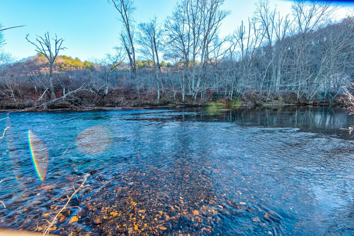 A tranquil view of the scenic river with bare trees lining the rocky riverbed, offering a peaceful natural setting perfect for fishing, kayaking, and observing wildlife.