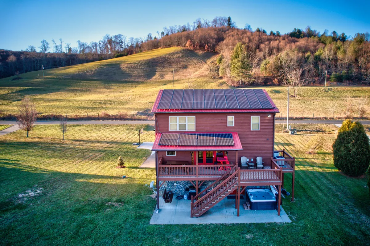 An exterior shot showing a stylish deck area with a hot tub, surrounded by a beautifully landscaped yard. Solar panels on the roof signal eco-friendly living, and the space is set for relaxation and gatherings, whether soaking in the tub or simply unwinding as the sun sets.