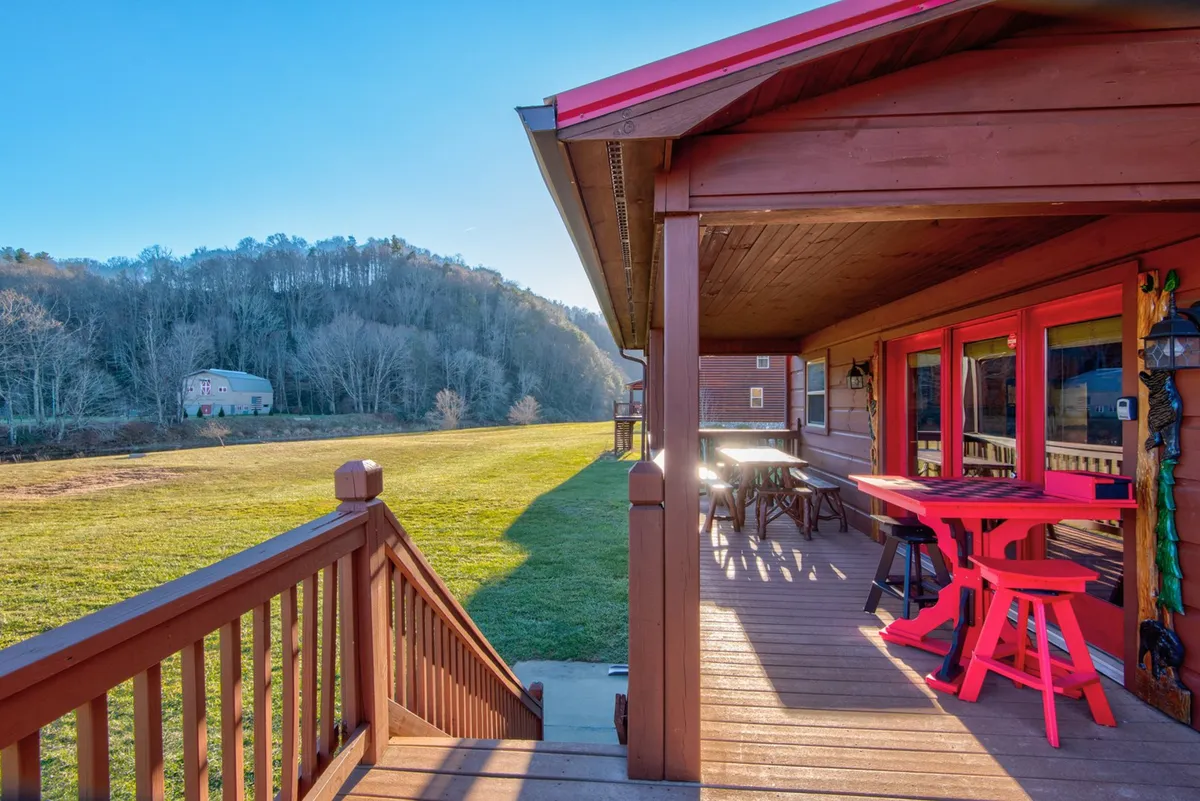 A cheerful deck scene with a red table and chairs, deck railing, and mountains in the distance. The setting exudes tranquility, encouraging outdoor dining or quiet moments taking in the sunset and starry skies.